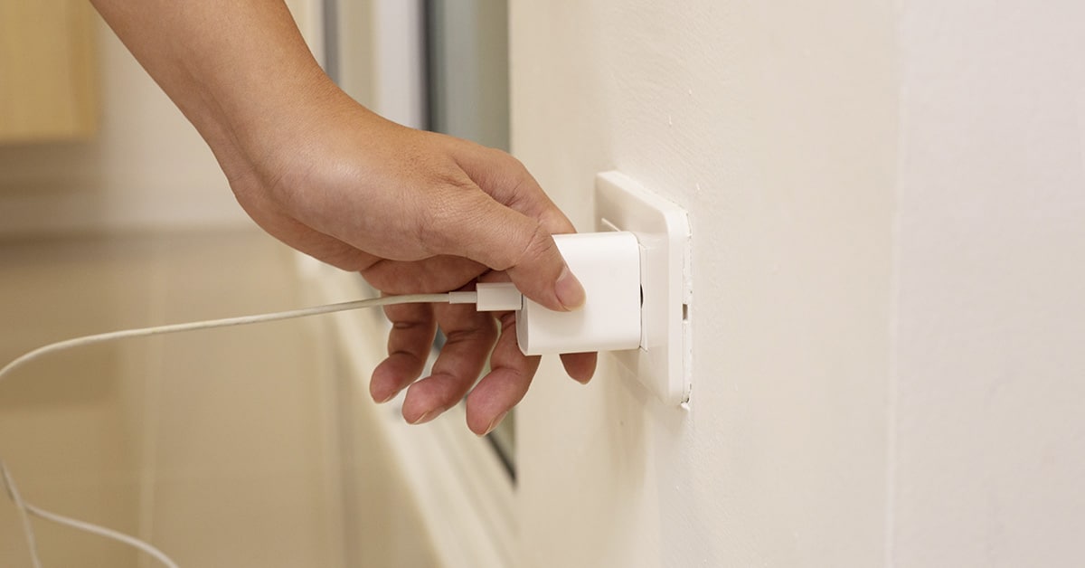 Main débranchant un chargeur de prise murale