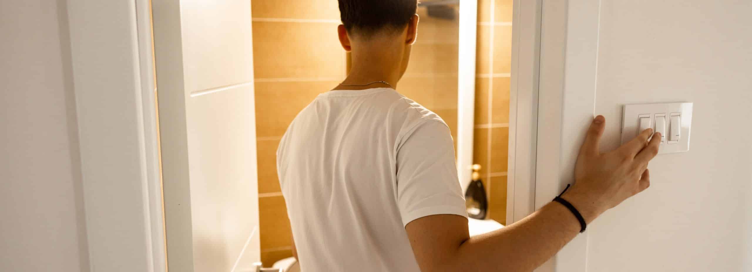 Homme éteignant la lumière dans une salle de bain