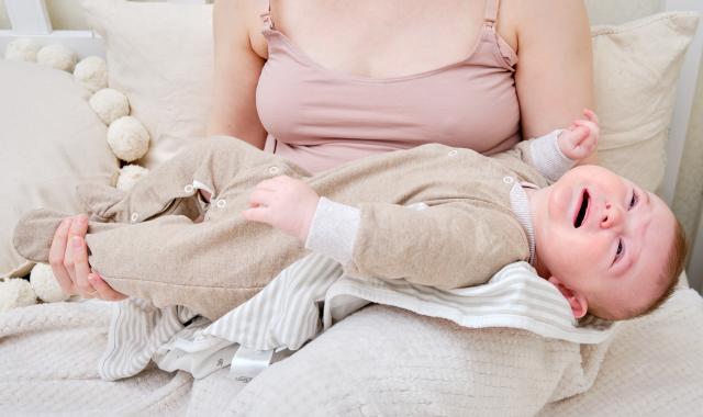 Jeune mère allaitant son bébé avec un air préoccupé