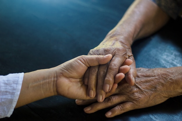 Fille tenant la main de sa mère âgée