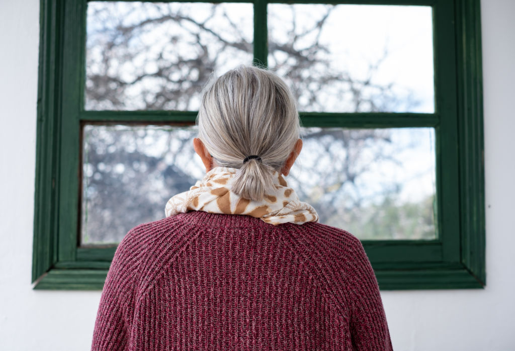 Femme âgée aux cheveux gris regardant par la fenêtre